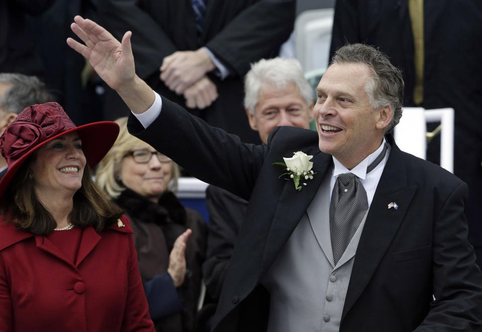 Virginia Gov. Terry McAuliffe, right, waves to supporters alongside his wife Dorothy during inaugural ceremonies at the Capitol in Richmond, Va., Saturday, Jan. 11, 2014. Former U.S. Secretary of State Hillary Rodham Clinton, left, and former U.S. President Bill Clinton look on in the background. McAuliffe is the 72nd governor of Virginia. (AP Photo/Patrick Semansky)