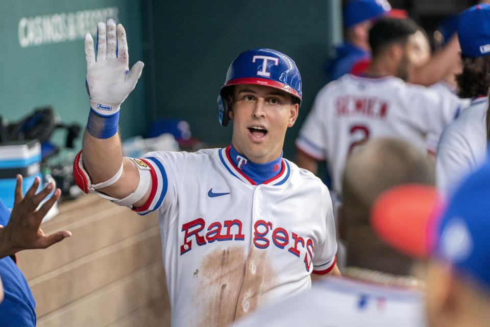 Texas Rangers' Nathaniel Lowe is congratulated in the dugout after a two-run home run that also scored Mitch Garver during the second inning of a baseball game against the Washington Nationals, Saturday, June 25, 2022, in Arlington, Texas. (AP Photo/Jeffrey McWhorter)
