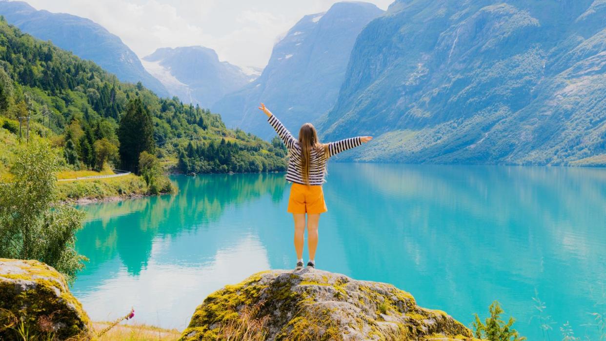 woman tourist admiring summer with scenic view of lake lovatnet in norway