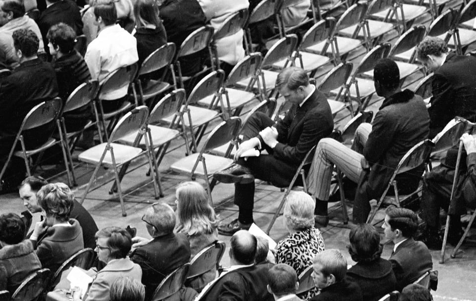 FILE - In this Nov. 15, 1970, file photo, Marshall assistant football coach Red Dawson, center, sits alone during a memorial service at the Veterans Memorial Field House in Huntington, W.Va., honoring the 75 people killed in a plane crash the night before. Marshall will mark the 50th anniversary of the plane crash that killed all 75 aboard on Saturday, Nov. 14, 2020, on the campus in Huntington. (Lee Bernard/The Herald-Dispatch via AP, File)