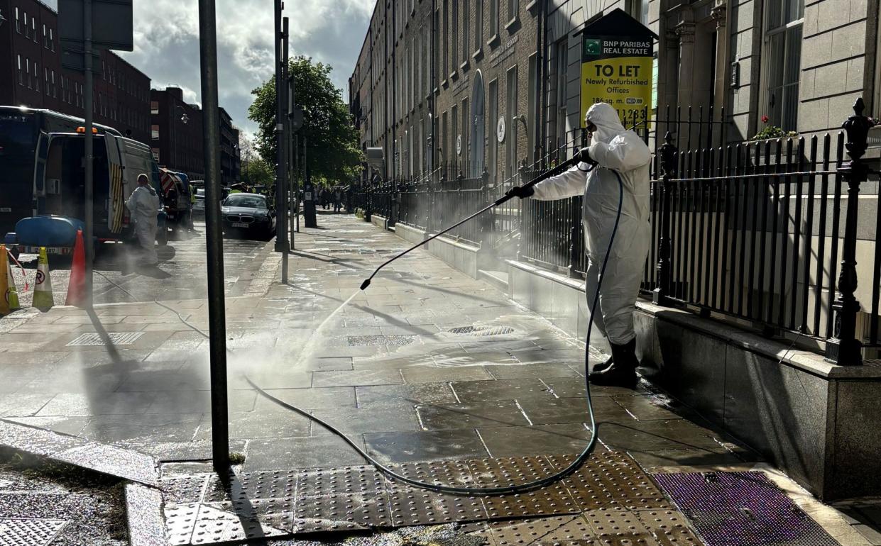 A worker cleans the pavement after migrant tents were removed