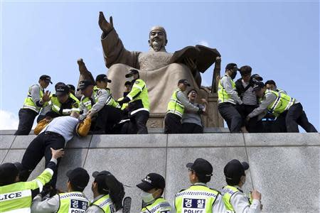 Policemen detain university students on a statue of King Sejong the Great during a protest against South Korean President Park Geun-hye, in central Seoul May 8, 2014. REUTERS/Han Jae-ho