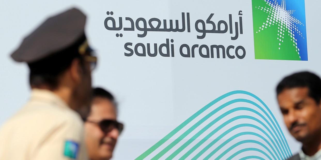 Logo of Aramco behind security personnel.