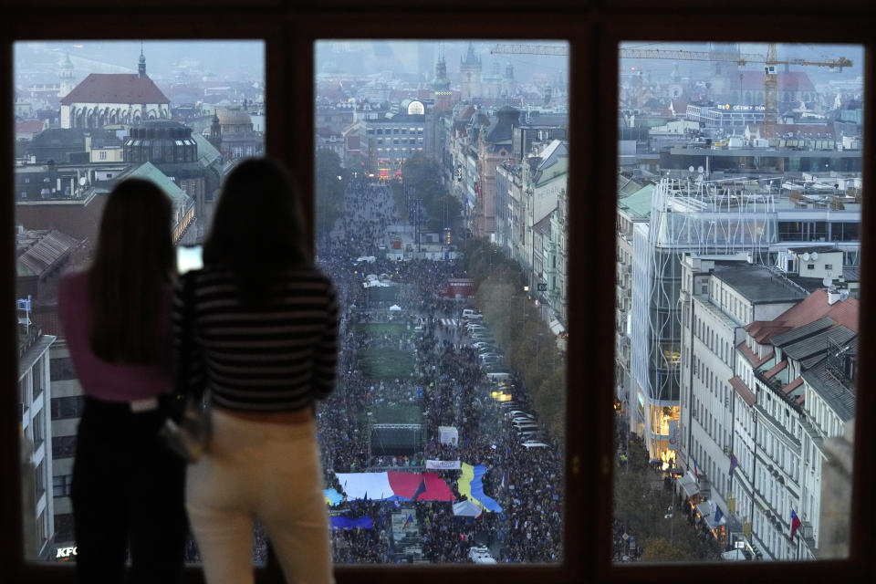 Women look from a window of the National Museum as tens of thousands of people gathers for an anti-war protest in Prague, Czech Republic, Sunday, Oct. 30, 2022. (AP Photo/Petr David Josek)