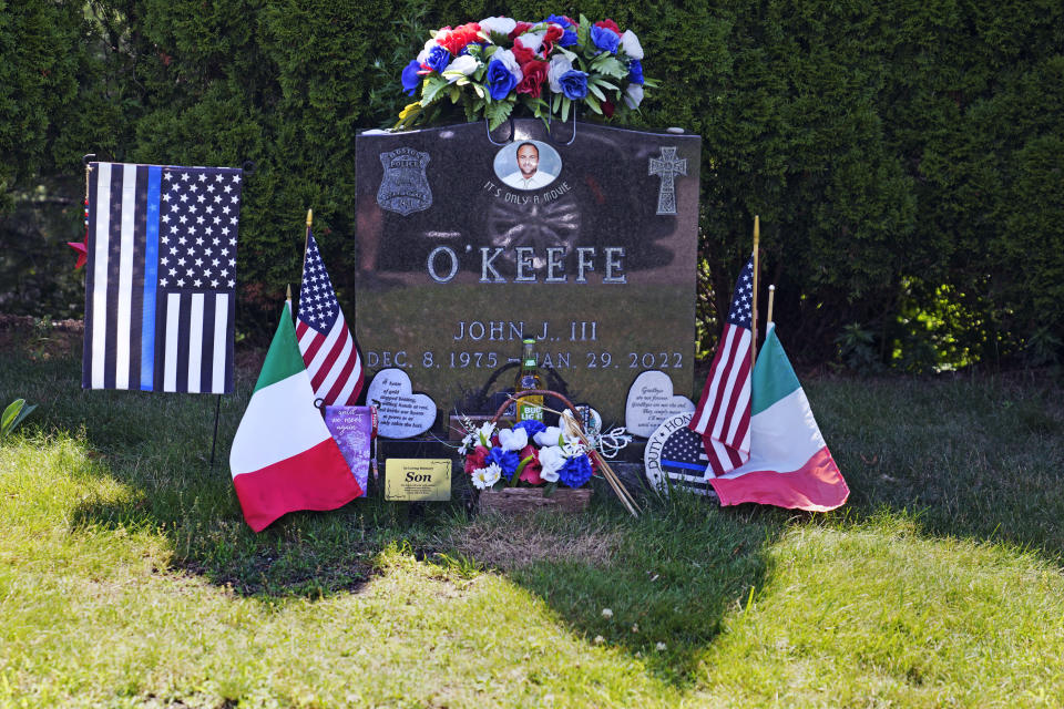 Flags, flowers and remembrances flank the headstone of John O'Keefe, a Boston police officer, at Blue Hill Cemetery, Thursday, June 27, 2024, in Braintree, Mass. A jury is deliberating the fate of O'Keefe's girlfriend, Karen Read, who is charged with second-degree murder in O'Keefe's death. (AP Photo/Charles Krupa)