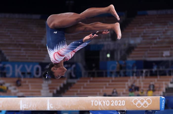 A gymnast midair and facing the balance beam with legs at a 90-degree angle