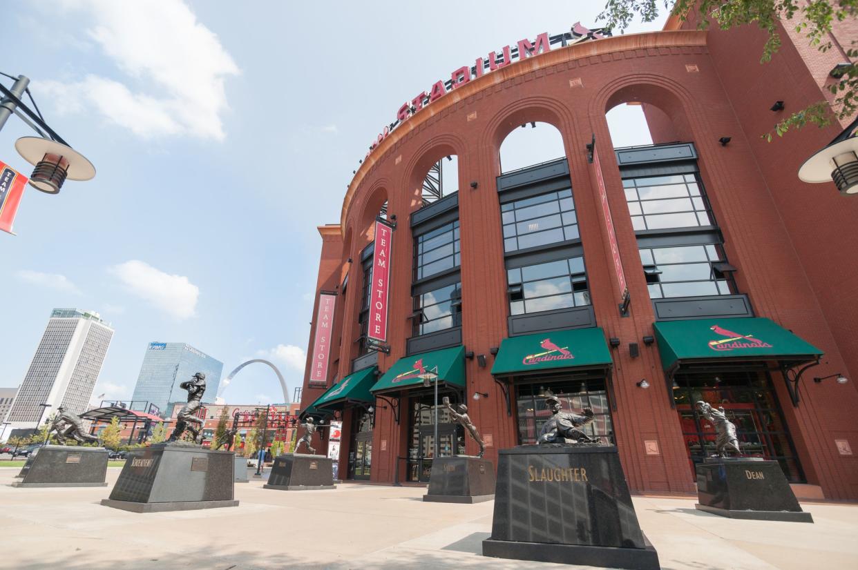 Front exterior of Busch Stadium, St. Louis, Home of the St. Louis Cardinals with several bronze statues of baseball greats with downtown in the background
