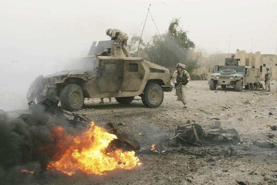 FILE - U.S. soldiers check an armored vehicle moments after it was damaged by a car bomb in Abu Ghraib, West of Baghdad, Iraq, April 3 2005. One soldier was lightly injured in the blast, and treated on the scene in the rear vehicle. (AP Photo/Jerome Delay, File)