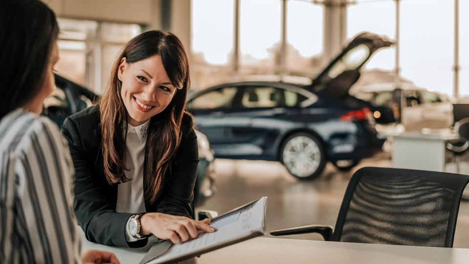 female car dealer showing customer paperwork