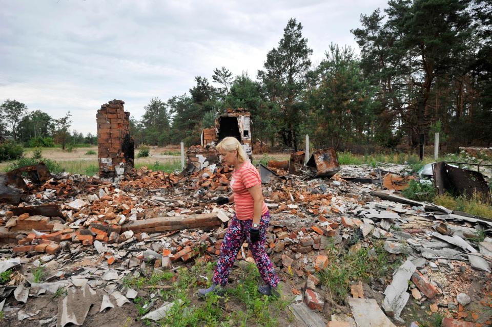 A woman walks amid debris of a house destroyed during Russia's invasion of Ukraine in the village of Teterivske, Kyiv region on July 9, 2022.