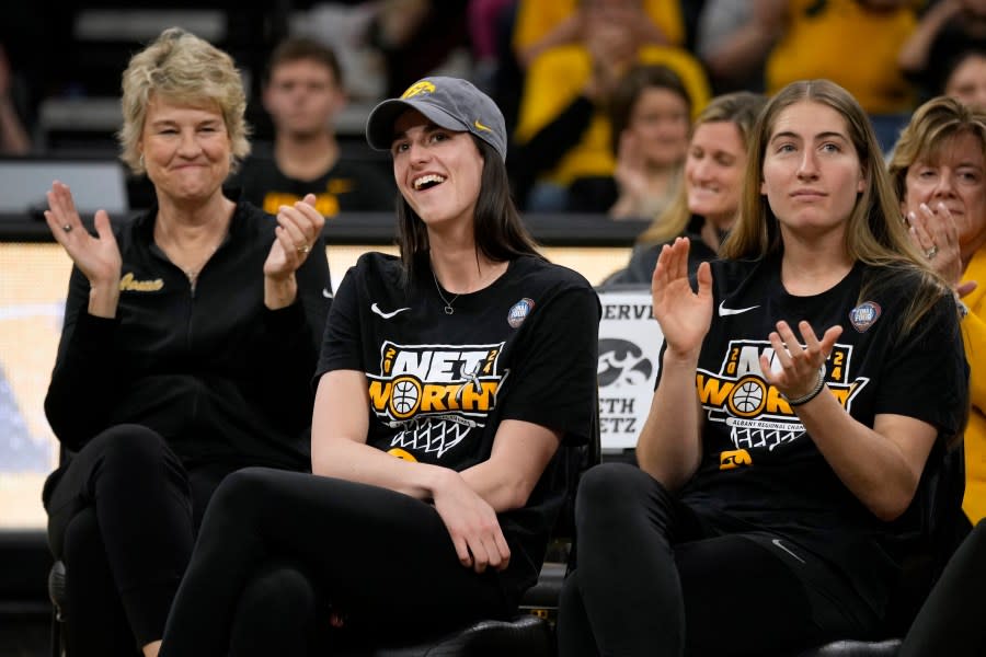 Iowa guard Caitlin Clark, center, sits with coach Lisa Bluder, left, and guard <a class="link " href="https://sports.yahoo.com/wnba/players/10181/" data-i13n="sec:content-canvas;subsec:anchor_text;elm:context_link" data-ylk="slk:Kate Martin;sec:content-canvas;subsec:anchor_text;elm:context_link;itc:0">Kate Martin</a>, right, as she finds out her number will be retired, during an Iowa women’s basketball team celebration Wednesday, April 10, 2024, in Iowa City, Iowa. Iowa lost to South Carolina in the college basketball championship game of the women’s NCAA Tournament on Sunday. (AP Photo/Charlie Neibergall)