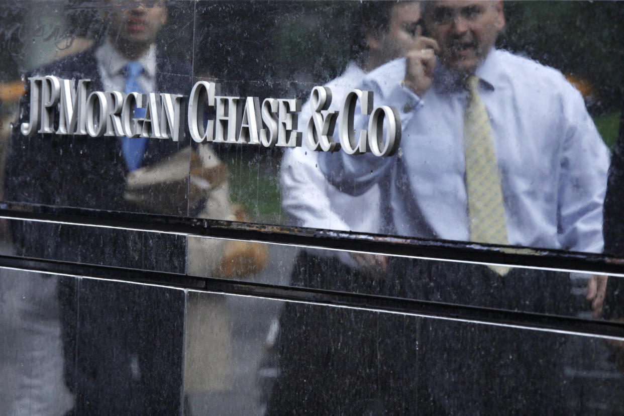 Commuters are reflected in stone as they walk past the JP Morgan headquarters in New York May 22, 2012.  JPMorgan Chase & Co has been hit with a lawsuit brought on behalf of employees whose retirement holdings fell in value after the largest U.S. bank revealed a surprise $2 billion trading loss earlier this month.  REUTERS/Eduardo Munoz (UNITED STATES - Tags: BUSINESS EMPLOYMENT LOGO)