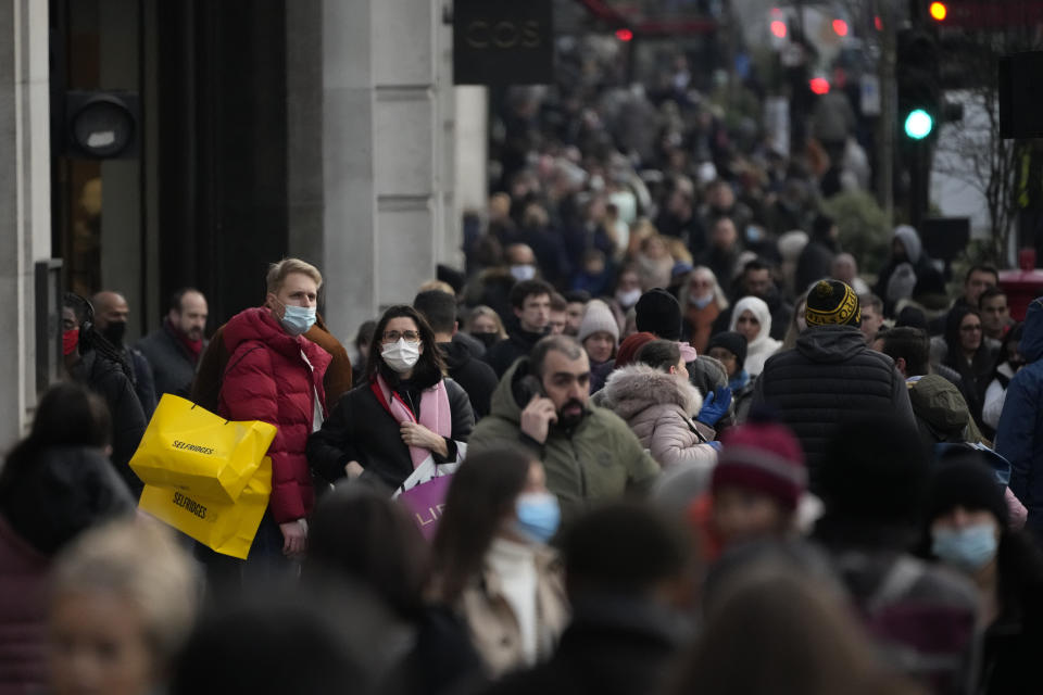 People stand holding shopping bags on Regent Street in London, Monday, Nov. 29, 2021. Countries around the world slammed their doors shut again to try to keep the new omicron variant at bay Monday, even as more cases of the mutant coronavirus emerged and scientists raced to figure out just how dangerous it might be. In Britain, mask-wearing in shops and on public transport will be required, starting Tuesday. (AP Photo/Matt Dunham)