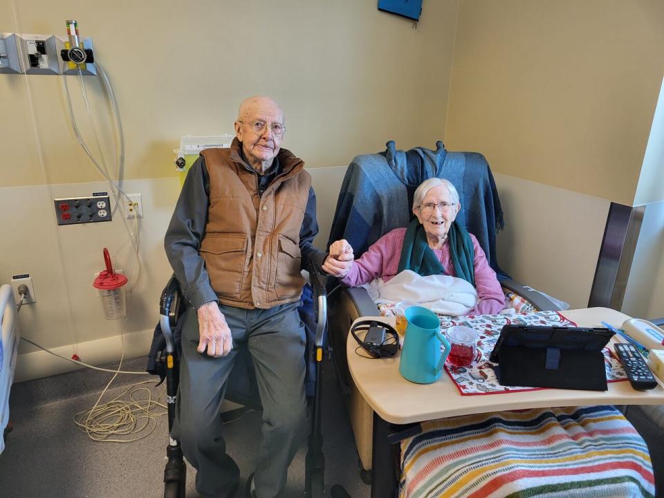 Lloyd Kostiuck, 99, of Watson Lake, Yukon, sits with his wife Evelyn, 95, at Whistle Bend Place in Whitehorse. Lloyd must travel five hours to visit Evelyn as there are no long-term care options in his community. (Cliff Kostiuck - image credit)