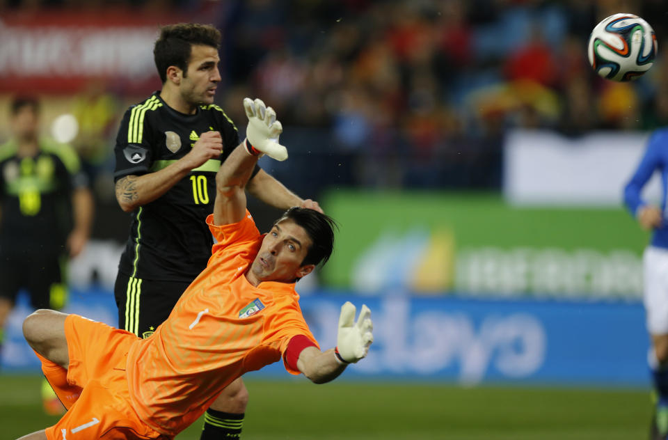 Italy's goalkeeper Gianluigi Buffon, right, tries to make a save from a shot by Cesc Fabrigas, left, that went over the bar during a friendly soccer match at the Vicente Calderon stadium in Madrid, Wednesday March 5, 2014. (AP Photo/Paul White)