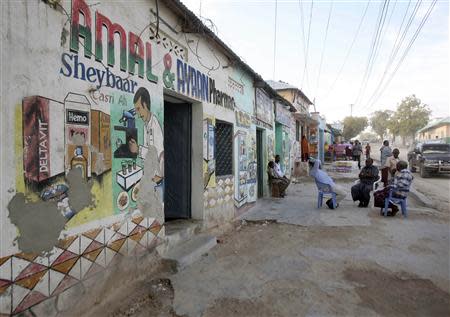 Men sit in front of a pharmacy in southern Mogadishu October 8, 2013. REUTERS/Feisal Omar