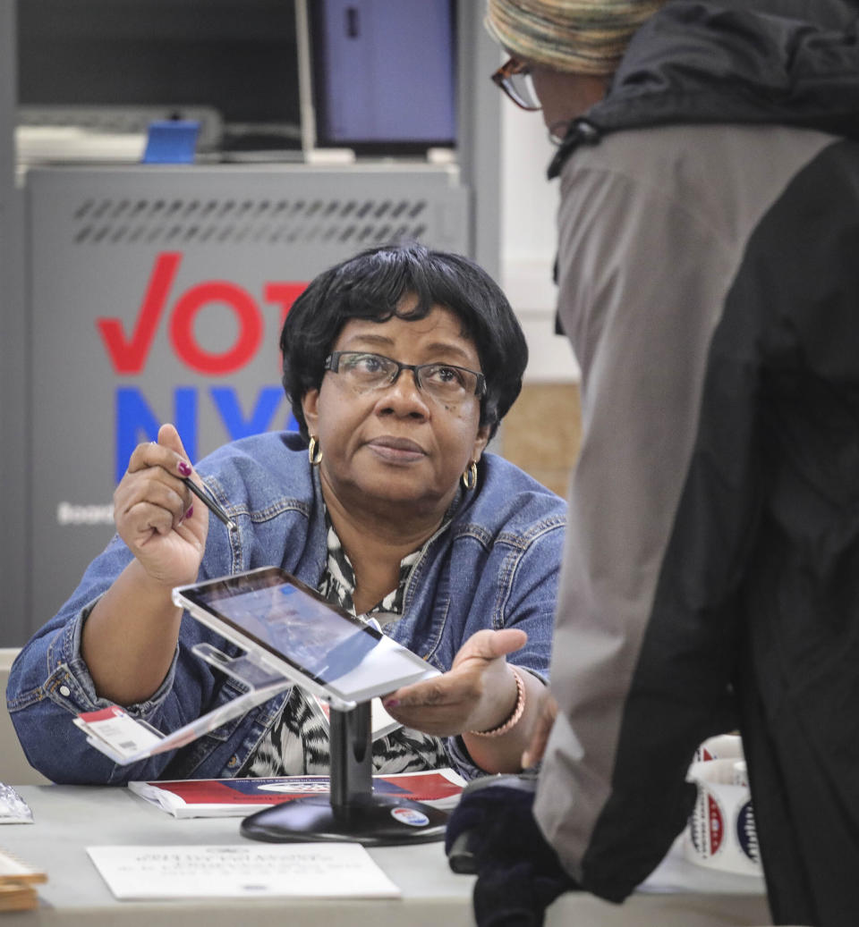 FILE - Phillis Montague-Paul, a polling site inspector, processes a voter using the new E-Poll Book tablet, during early voting at Brooklyn's Clara Barton High School, Oct. 26, 2019, in New York. (AP Photo/Bebeto Matthews, File)