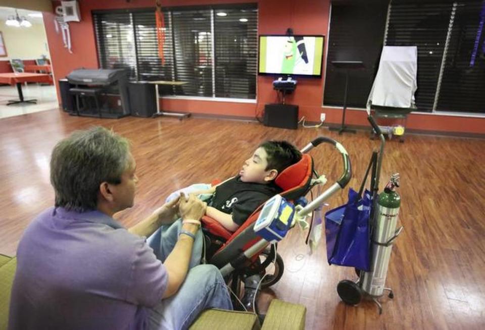 In an open living room at a pediatric nursing home, Jose Buraschi talks to his son Alessio, sharing family news. Alessio was moved to a nursing home because of intractable seizures.