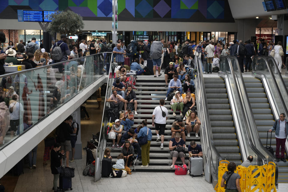 Viajeros sentados en las escaleras de la estación Gare de Montparnasse, el día de la inauguración de los Juegos Olímpicos de París, el viernes 26 de julio de 2024 en París, Francia. Las líneas de tren de alta velocidad en Francia sufrieron varios “actos maliciosos” que afectaron gravemente al tráfico el viernes, el día en el se celebraba una ceremonia de apertura de alto riesgo para los Juegos Olímpicos de París, según dijo el viernes la compañía ferroviaria SNCF. (AP Foto/Yasin Dar)