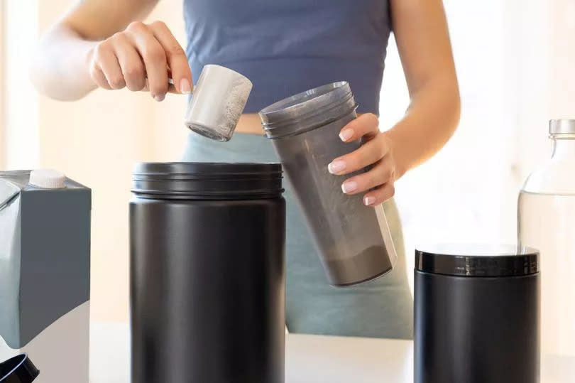 Woman preparing protein shake at home.