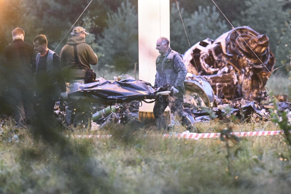 Dos personas trasladan una bolsa para cadáveres del lugar donde se estrelló un avión privado, cerca de la localidad de Kuzhenkino, en la región de Tver, Rusia, el 24 de agosto de 2023. (AP Foto)