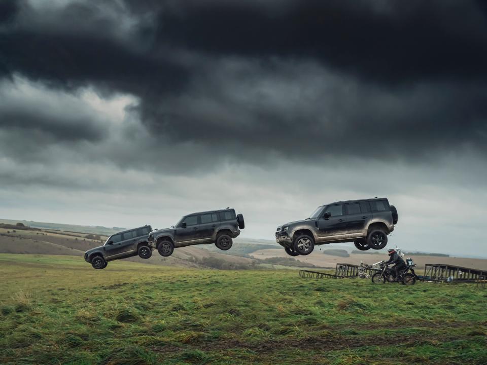 Land Rover Defender 110s fly through the air during a stunt scene from "No Time to Die".