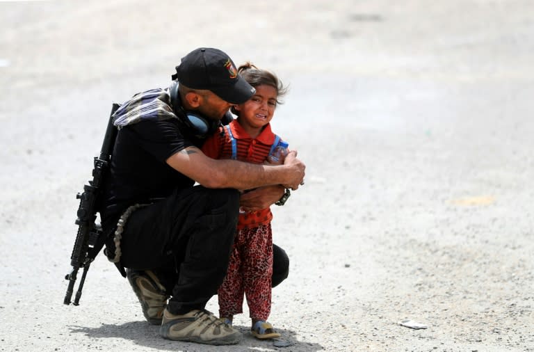 An Iraqi soldier helps a girl whose family has fled their home in the west of Mosul on May 26, 2017