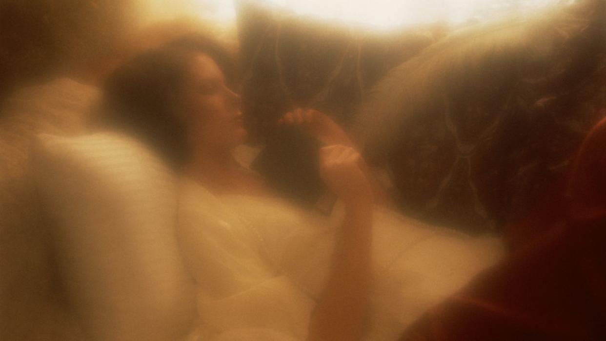 a blurry woman lying down and holding a book