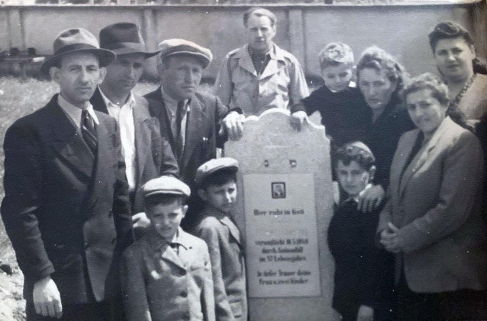 The Eisenberg and Brandspiegel families gather around the tombstone of Abraham Eisenberg at the Hallein Displaced Persons Camp in Austria in June 1948. (Courtesy Ruth Brandspiegel via AP)