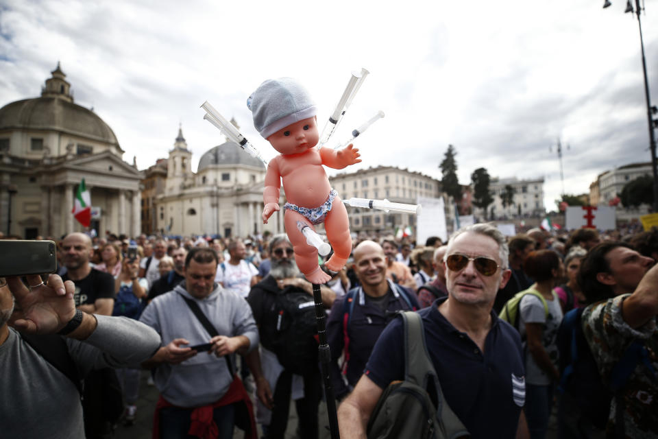 A doll with syringes is shown by a demonstrator during a protest, in Rome, Saturday, Oct. 9, 2021. Thousands of demonstrators protested Saturday in Rome against the COVID-19 health pass that Italian workers, both the public and private sectors, must display to access their workplaces from Oct. 15 under a government decree. (Cecilia Fabiano/LaPresse via AP)
