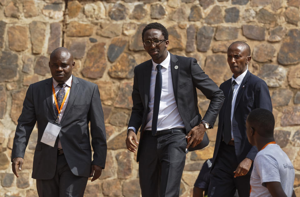 Rwandan-born French MP Herve Berville, center, representing France, arrives to lay a wreath at the Kigali Genocide Memorial in Kigali, Rwanda Sunday, April 7, 2019. Rwanda is commemorating the 25th anniversary of when the country descended into an orgy of violence in which some 800,000 Tutsis and moderate Hutus were massacred by the majority Hutu population over a 100-day period in what was the worst genocide in recent history. (AP Photo/Ben Curtis)