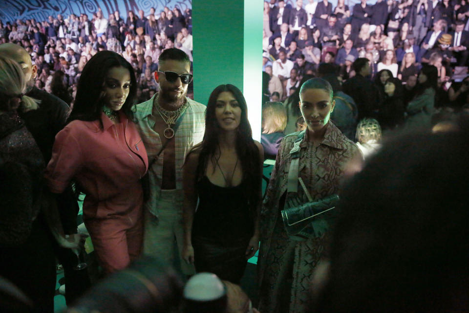 In this Tuesday, Dec. 3, 2019, photo, model Winnie Harlow, from left, singer Maluma, Kourtney Kardashian and Kim Kardashian wait for the Christian Dior pre-fall 2020 men's fashion show to start during Miami Art week, in Miami. (AP Photo/Brynn Anderson)