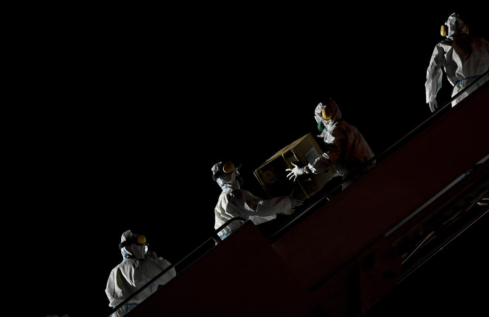 FILE - In this March 30, 2020, file photo, Venezuelan workers wearing protective face masks and suits as a preventive measure against the spread of the coronavirus unload boxes of humanitarian aid as medical supplies and specialists from China arrive to Simon Bolivar International Airport in La Guaira, Venezuela. A new snapshot of the frantic global response to the coronavirus pandemic shows some of the world's largest government donors of humanitarian assistance are buckling under the strain and overall aid commitments have dropped by a third from the same period last year. (AP Photo/Matias Delacroix, File)