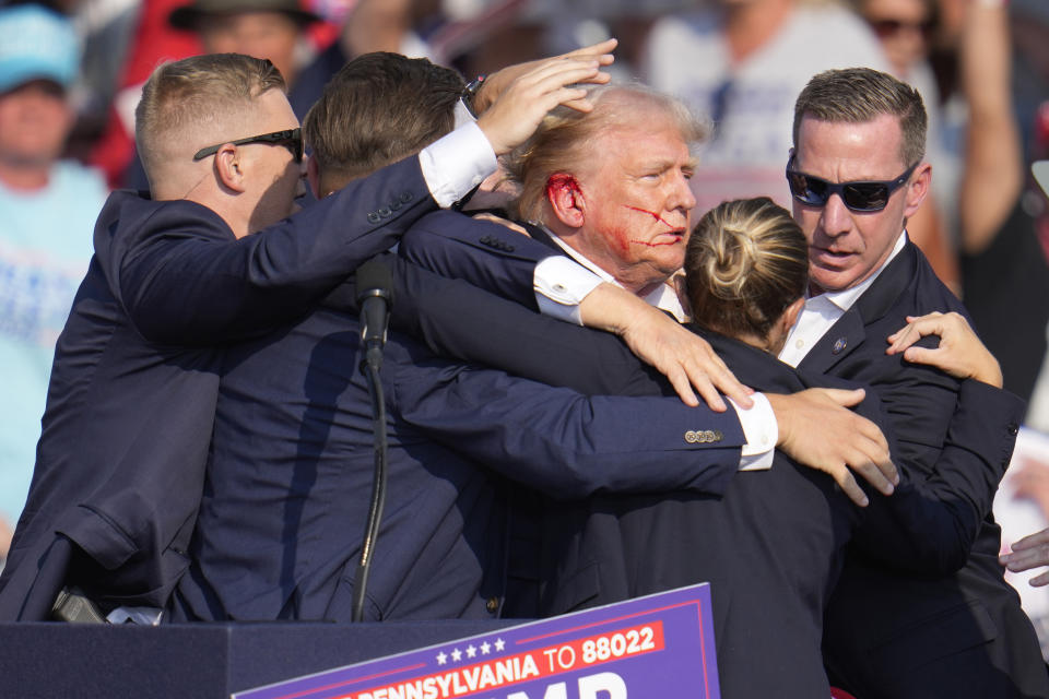 Former President Donald Trump is surrounded by U.S. Secret Service agents as he is helped off the stage after being shot at a campaign rally in Butler, Pa., on July 13, 2024. (Gene J. Puskar/AP)