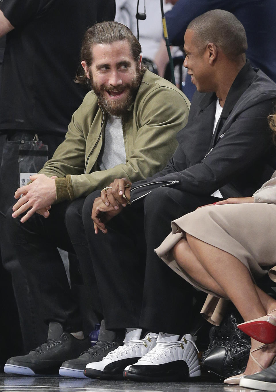 Actor Jake Gyllenhaal, left, and entertainer Jay-Z talk during a timeout during Game 3 of an Eastern Conference semifinal NBA playoff basketball game between the Miami Heat and the Brooklyn Nets, Saturday, May 10, 2014, in New York. (AP Photo/Julie Jacobson)