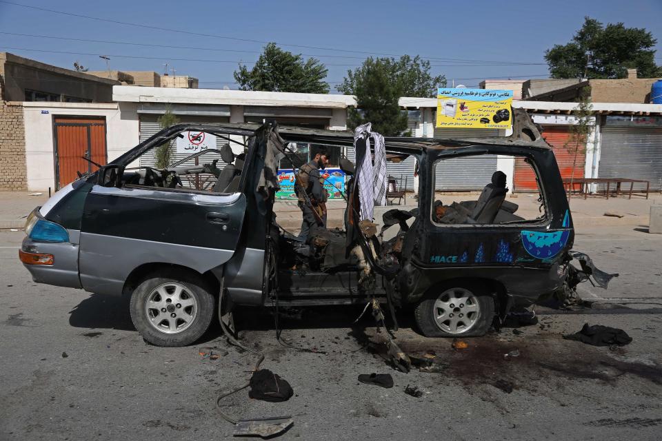 A security personnel stands next to a damaged vehicle at the site of an explosion in Kabul on June 3, 2021. At least seven people have been killed in two new attacks on minivans. (AFP via Getty Images)