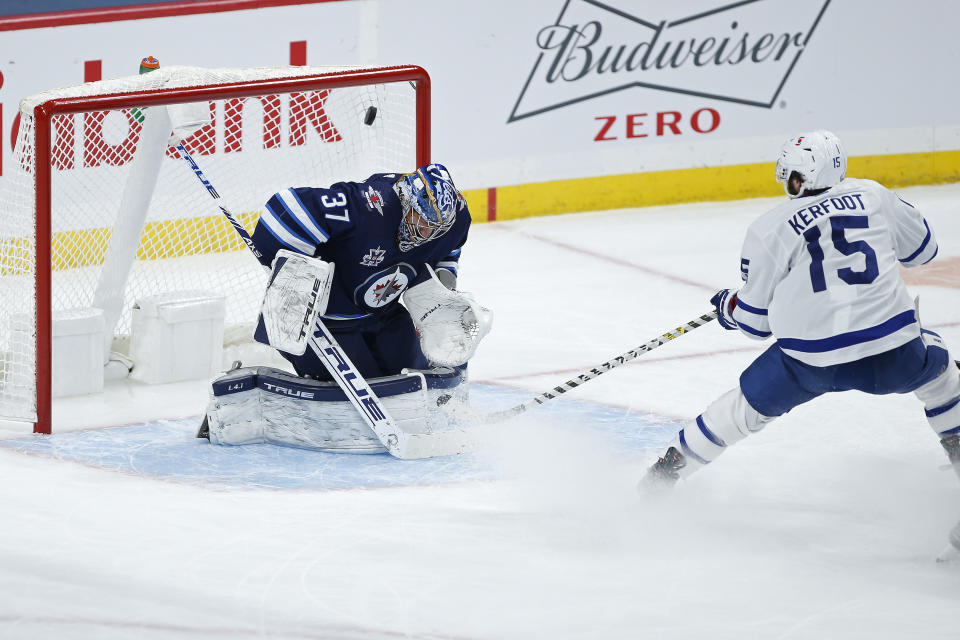 Toronto Maple Leafs' Alexander Kerfoot (15) scores on Winnipeg Jets goaltender Connor Hellebuyck (37) during the second period of an NHL hockey game Wednesday, March 31, 2021, in Winnipeg, Manitoba. (John Woods/The Canadian Press via AP)