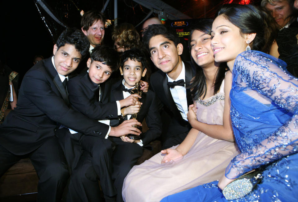 Group of "Slumdog Millionaire" cast members posing with an award at a formal event