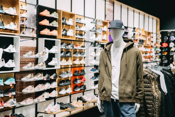 A mannequin and a wall of shoes inside a store