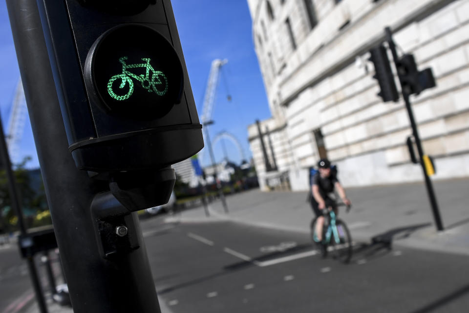 FILE - A man rides his bicycle past a green traffic light, in London, Monday, May 18, 2020. In the COVID era, Paris, London and Brussels expanded their bike networks the most among the nine European cities studied and experienced the largest cycling increases in return. (AP Photo/Alberto Pezzali, File)