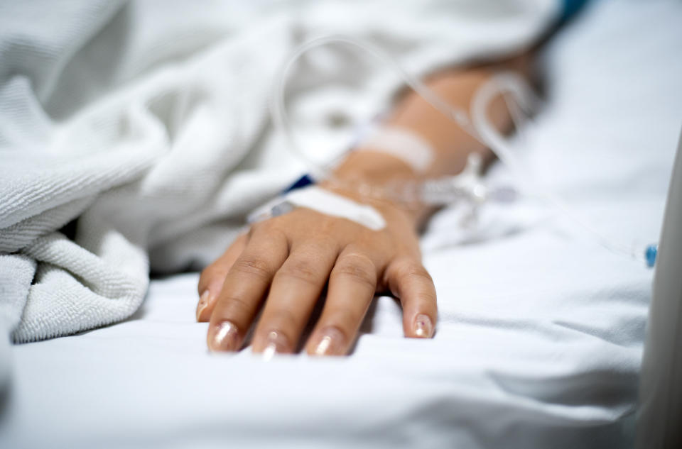 Arm of person in hospital bed, with a needle attached