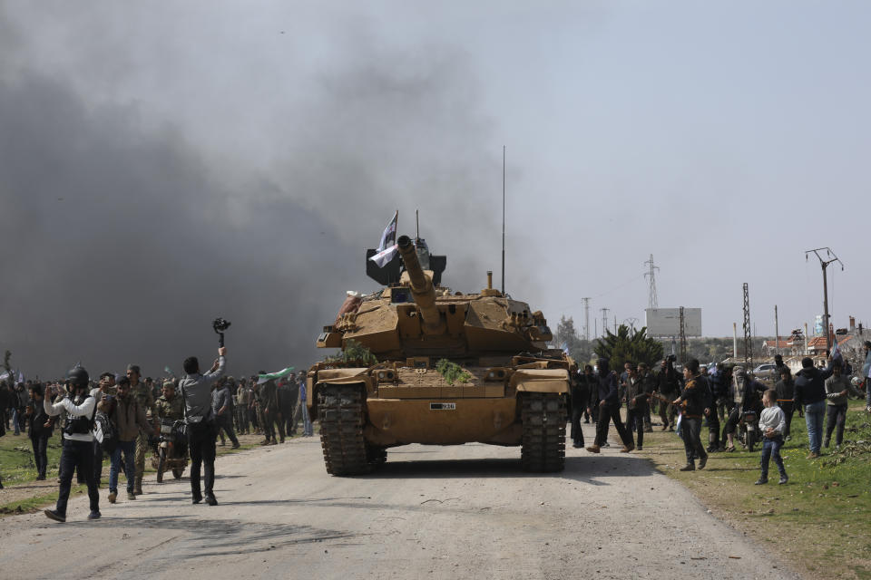 Syrians climb on a Turkish tank in Neyrab, Sunday, March 15, 2020 as they protest agreement on joint Turkish and Russian patrols in northwest Syria. Patrols on the M4 highway, which runs east-west through Idlib province, are part of a cease-fire agreed between Turkey and Russia after an escalation in fighting that saw the Turkish military in direct conflict with Syrian government troops.( (AP Photo/Ghaith Alsayed)