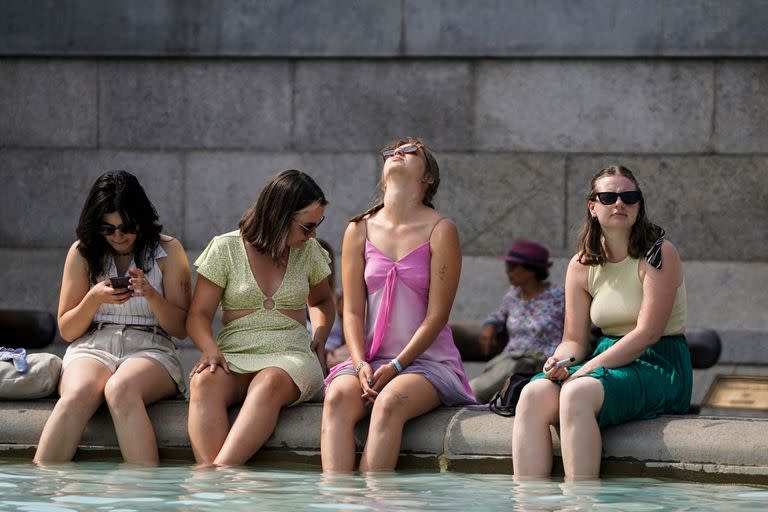 Un grupo de mujeres se refresca sumergiendo sus pies en la fuente de Trafalgar Square, en el centro de Londres, el 18 de julio de 2022