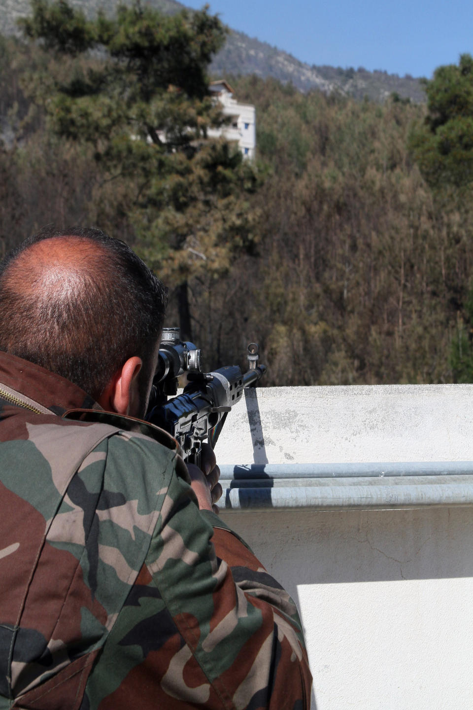 In this photo taken Thursday, March 27, 2014, a Syrian government soldier takes position during clashes with rebels in Misherfeh town in the province of Latakia, Syria. Syrian forces on Thursday bombarded rebel positions with artillery and warplanes in the Mediterranean coastal province of Latakia, trying to push back opposition fighters who over the past week made rare territorial gains in President Bashar Assad's ancestral heartland. (AP Photo)