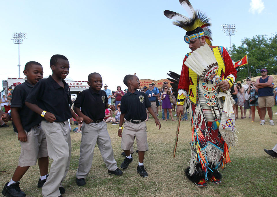 Children from the John Dilbert Charter School of New Orleans volunteer to dance with a member of the Ojibway tribe during a pow wow performance by Native Nations Intertribal at the Native American Village at the New Orleans Jazz and Heritage Festival in New Orleans, Friday, May 4, 2012. (AP Photo/Gerald Herbert)