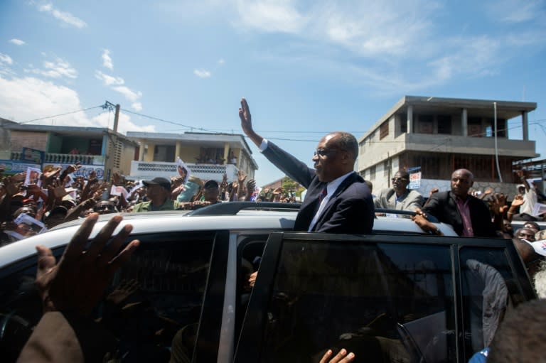 Former Haitian president Jean-Bertrand Aristide greets supporters in Port-au-Prince in a rare public outing to testify in a money laundering case