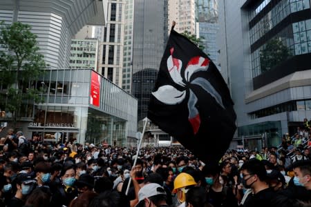 People hold up a black flag during a protest outside police headquarters to demand Hong Kong’s leaders step down and withdraw an extradition bill, in Hong Kong