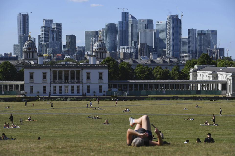 People sit on the grass and enjoy the hot weather in Greenwich Park in London, backdropped by the City of London buildings, after the introduction of measures to slowly bring the country out of lockdown, Tuesday May 19, 2020. The highly contagious COVID-19 coronavirus has impacted on nations around the globe, many imposing self isolation and exercising social distancing when people move from their homes. (Kirsty O'Connor / PA via AP)