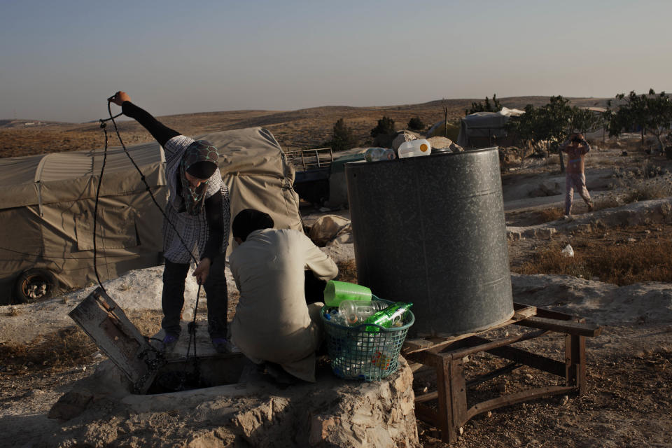 In this Friday, June 15, 2012 photo, Palestinian women collect water from a well in the West Bank town of Susiya. Palestinian herders in this hamlet have clung to arid acres spread over several West Bank hills for decades, even as Israel forced them to live off the grid while providing water and electricity to nearby Jewish settlements and unauthorized outposts. But the end seems near for Susiya's 200 residents: Citing zoning violations, Israel is threatening to demolish the village, including German-funded solar panels. (AP Photo/Bernat Armangue)