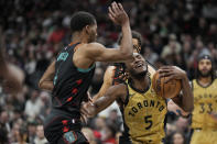 Toronto Raptors guard Immanuel Quickley (5) reacts as he battles Washington Wizards guard Jared Butler, left, for control of the ball during the first half of an NBA basketball game in Toronto on Sunday, April 7, 2024. There was no foul called on the play. (Frank Gunn/The Canadian Press via AP)